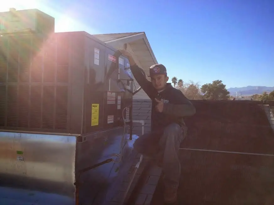 HVAC technician performing Air Duct Cleaning on a rooftop unit in Dos Palos