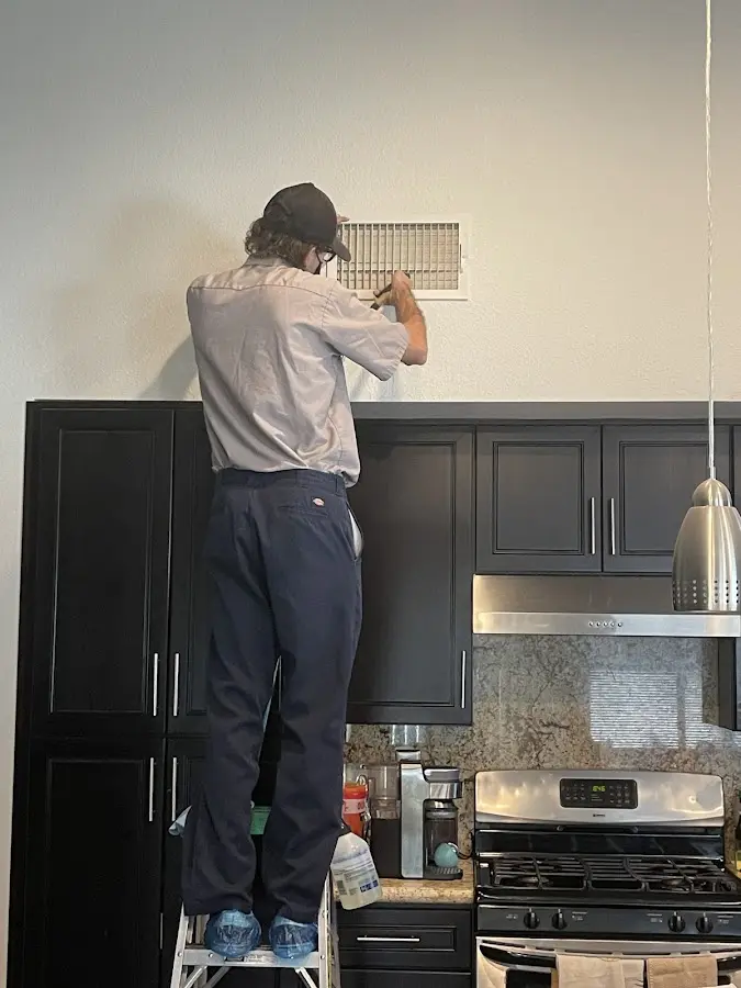 Technician inspecting an air vent during HVAC service in Dos Palos